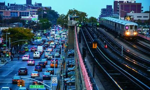 Cars sit in traffic while a train passes them by. 